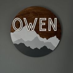 a wooden sign with the word oven on it and mountains in the backround