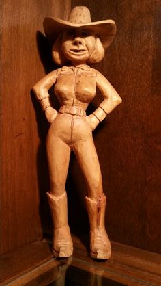 a wooden statue of a woman wearing a cowboy hat and holding her hands on her hips