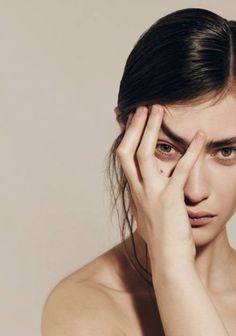 a woman holding her hand to her face while looking at the camera with an intense look on her face