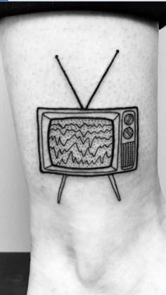 a small tv tattoo on the side of a person's leg, with an old television