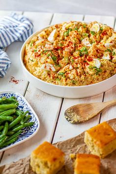 a casserole dish on a table with green beans and cornbreads next to it