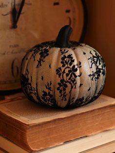 a black and white pumpkin sitting on top of a wooden table next to a clock