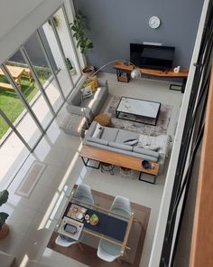 an overhead view of a living room and dining area with couches, coffee table, television, and windows