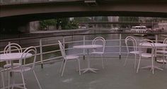 tables and chairs are set up on the deck of a boat under an overpass