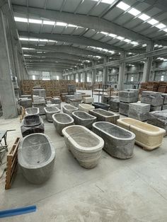 many different types of bathtubs in a large room with concrete walls and flooring