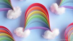 several rainbows with clouds in the middle on a blue background that appears to be made out of paper