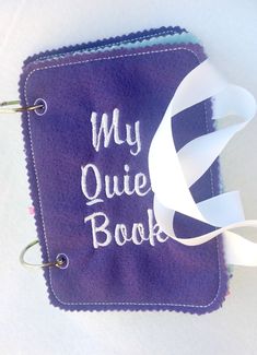 a purple book with the words my quiie book on it and a white ribbon