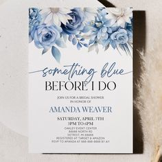 a blue and white floral bridal shower is displayed on a table next to feathers