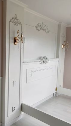 an empty room with white walls and gold trimmings on the door, along with a bench