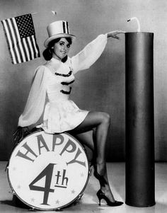 a woman sitting on top of a drum next to an american flag and the number four