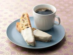 a cup of coffee and two pieces of biscuits on a blue plate with pink damask