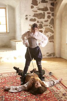 two people on the ground with swords in their hands and one person laying on the floor