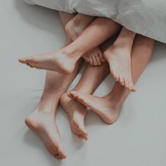 three bare feet sitting on top of a bed next to each other in front of a pillow