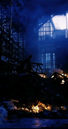 the silhouette of a man standing in front of a pile of rubble at night time