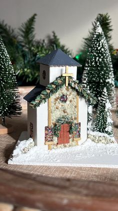 a small white church surrounded by trees and snow