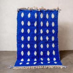 a blue rug with white dots and fringes on the bottom is sitting in front of a wall