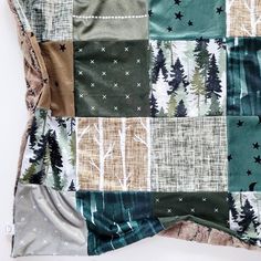 a patchwork blanket with trees and stars on it, sitting on top of a white surface