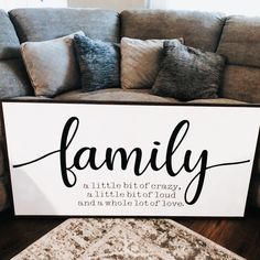 a family sign sitting on top of a wooden floor next to a couch and rug