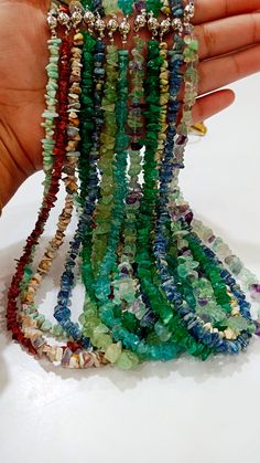 a hand is holding several bracelets that are made from glass beads and various colored stones