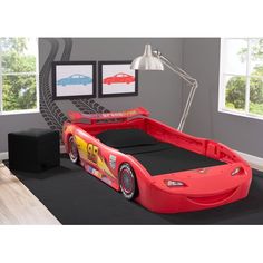 a child's bed with cars on it and a lamp next to the bed