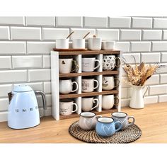 several coffee mugs are stacked on a shelf in front of a white brick wall