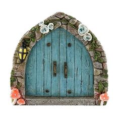 a blue door with flowers on it and a lantern in the middle, sitting next to mushrooms