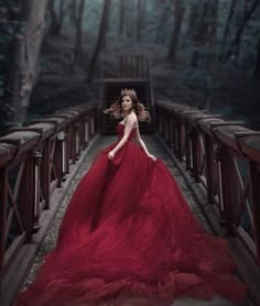 a woman in a red dress standing on a bridge