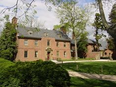 a large red brick building surrounded by lush green grass and trees on a sunny day