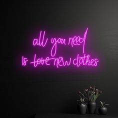 a neon sign that says, all you need is love new clothes on the wall