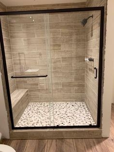 a walk in shower sitting next to a toilet on top of a hard wood floor