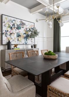 a dining room table and chairs in front of a painting