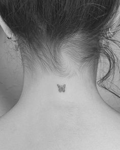 a small butterfly tattoo on the back of a woman's neck