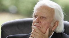 an older man sitting in a chair with his chin resting on his hand and looking off to the side