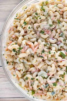 a bowl filled with macaroni salad on top of a wooden table