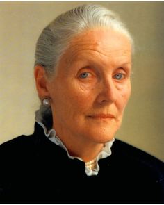 an old woman with white hair and blue eyes looking at the camera while wearing earrings