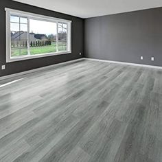 an empty living room with gray walls and wood flooring is seen in this image