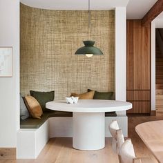 a white table sitting under a green lamp in a room next to a wooden floor