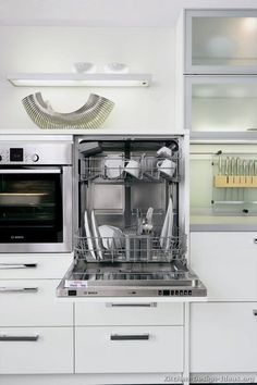 an open dishwasher in a kitchen next to a wall mounted oven and microwave