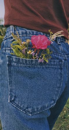 a person's jeans with a flower in the back pocket and grass growing out of it