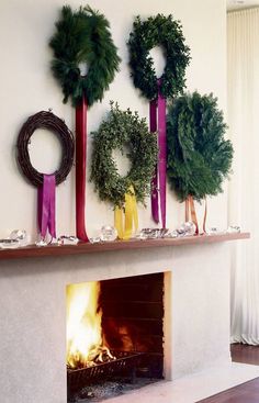 christmas wreaths are hung on the wall above a fireplace and below a table with wine glasses