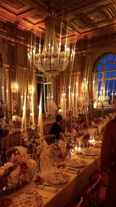 a fancy dining room with candles lit up in the ceiling and chandeliers hanging from the ceiling