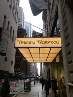 people walking down the sidewalk in front of a building with a sign that says whinene westwood