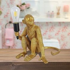 a monkey figurine holding a light bulb on top of a table