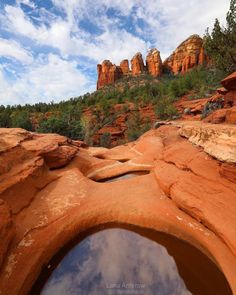 a small pool in the middle of some red rocks