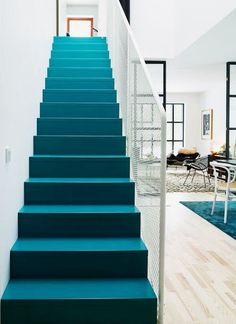 blue stairs leading up to a living room with white walls and wood flooring in the background