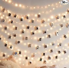 a bedroom with lights strung from the ceiling and pictures hung on the wall above it