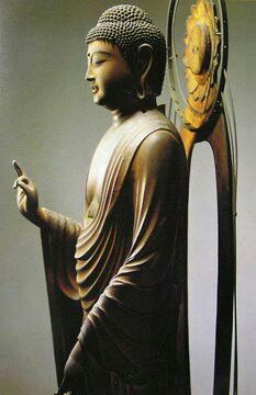 a buddha statue holding a cell phone next to a clock