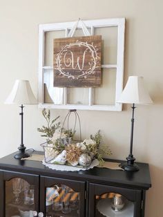 an image of a sign on the wall above a table with lamps and vases