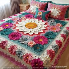 a bed covered in pink, white and blue crocheted bedspread with flowers on it