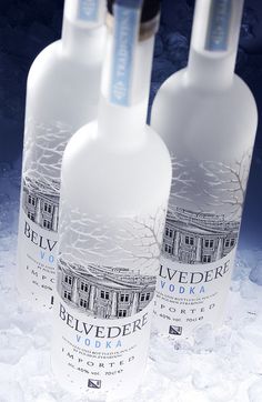 three bottles of vodka sitting on top of snow in front of a dark blue background